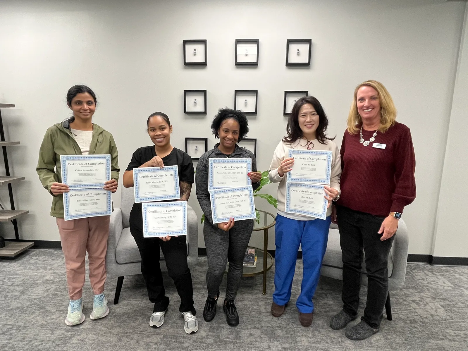 Four Atlanta graduates hold certificates beside their Academy instructor