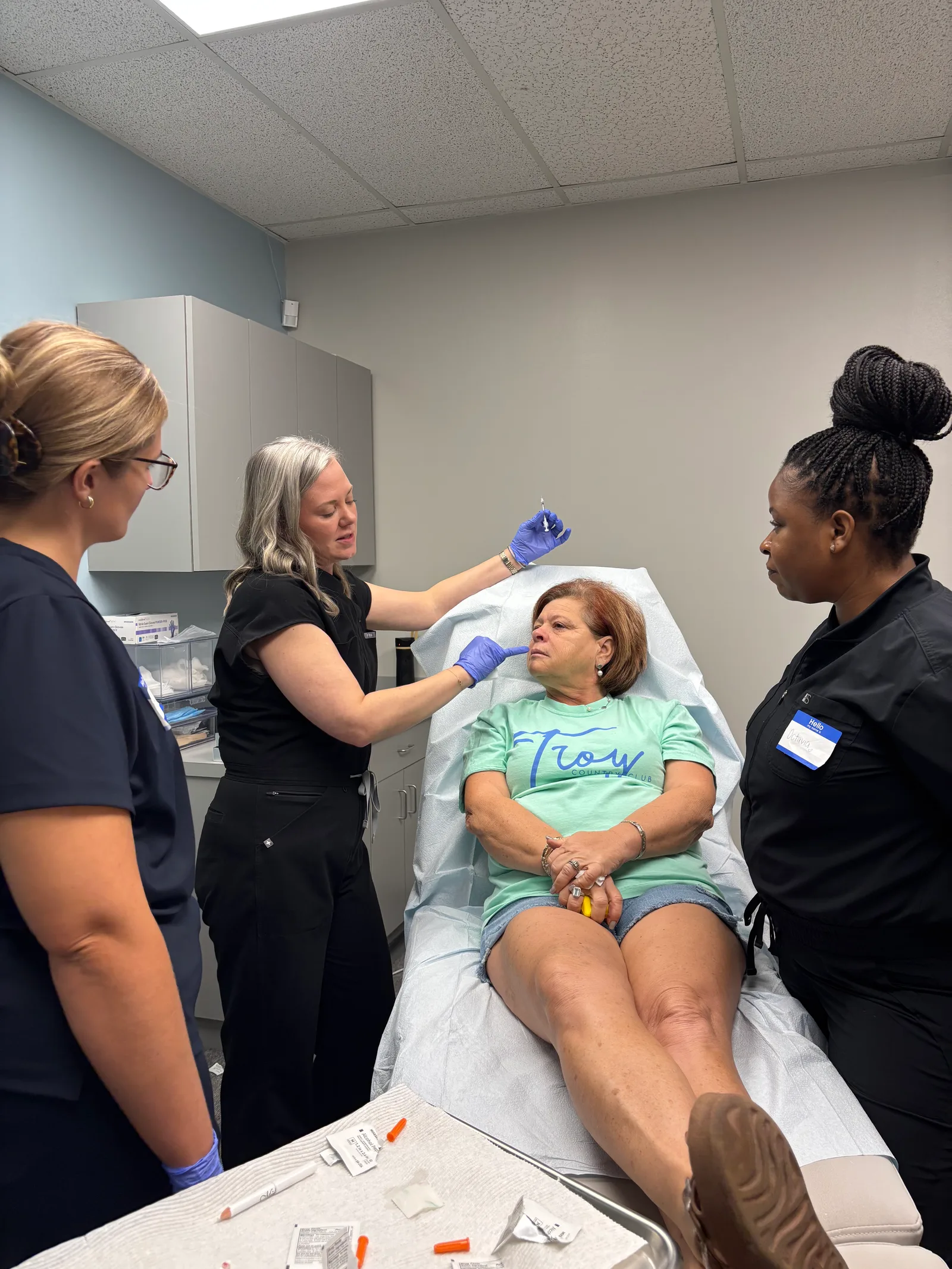 An instructor discusses a technique with students beside a live model