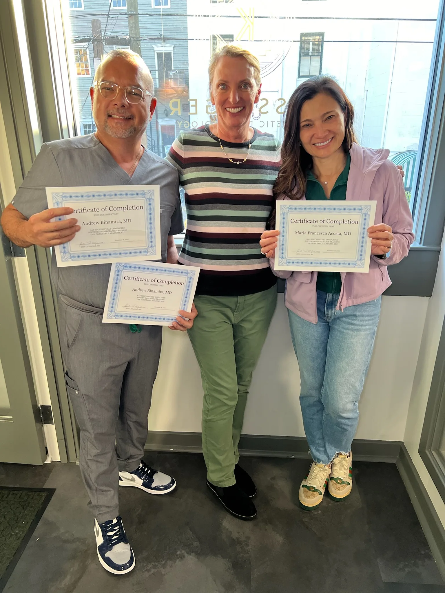 Two Savannah graduates hold certificates beside an Academy instructor