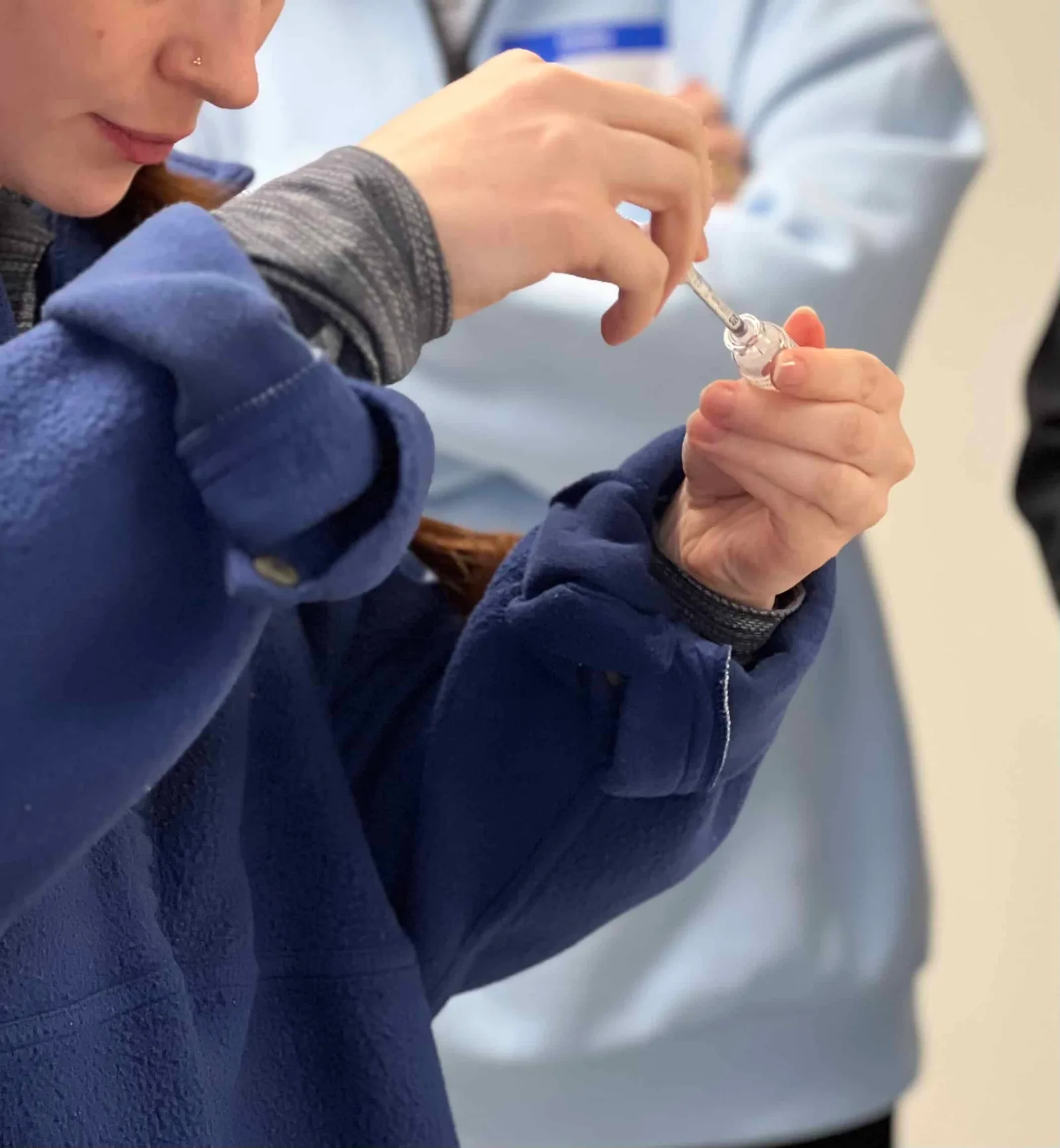 A close view of a participant preparing a syringe during training